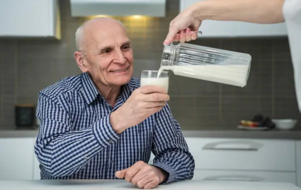 Persona mayor a la que se le está sirviendo un vaso de leche