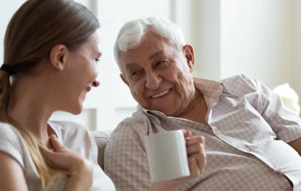 Foto de un anciano y una chica joven hablando y tomando un café