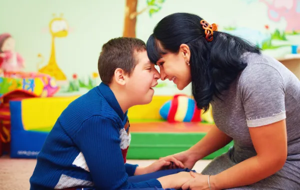 Foto de un chico con una discapacidad acompañado de una mujer que le coge de las manos