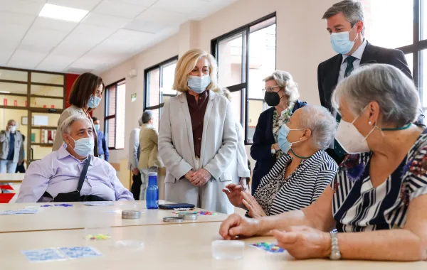 Foto de un centro social con varias personas mayores hablando en grupo con una trabajadora social