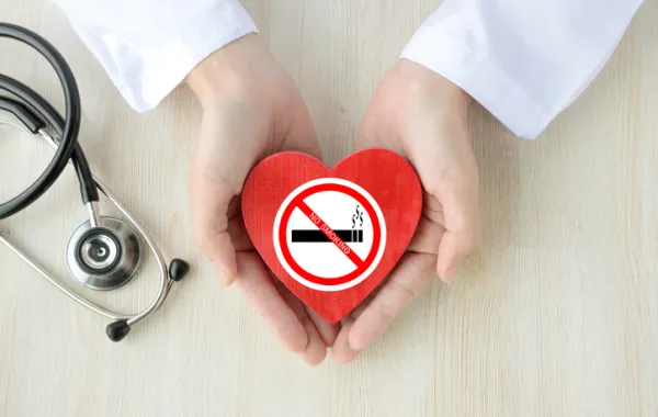 Foto de las manos de un médico que sostiene un dibujo de un corazón con el simbolo de dejar de fumar