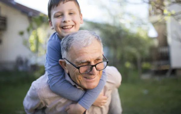 Foto de un abuelo que lleva en hombros a su nieto