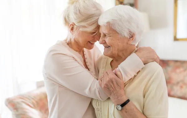 Foto de una señora mayor acompañada por otra señora más joven que la abraza