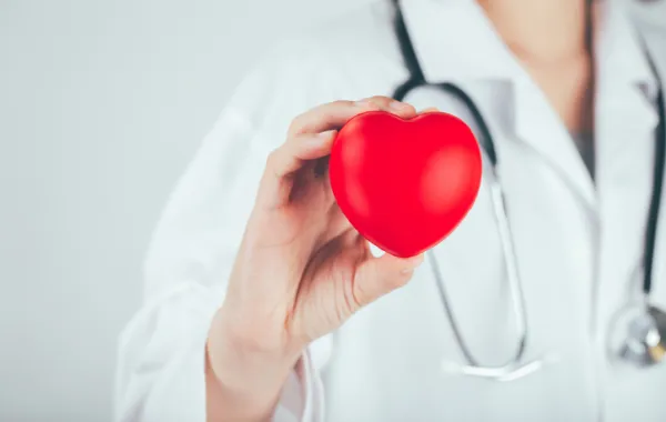 Foto de una doctora que sostiene en su mano un corazón de espuma