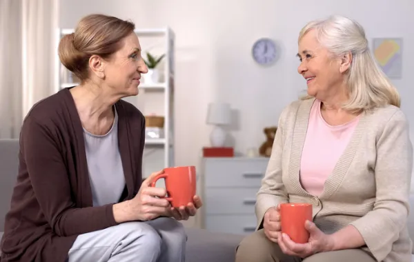 Foto de una señora mayor tomando un cafe y charlando con otra señora más joven