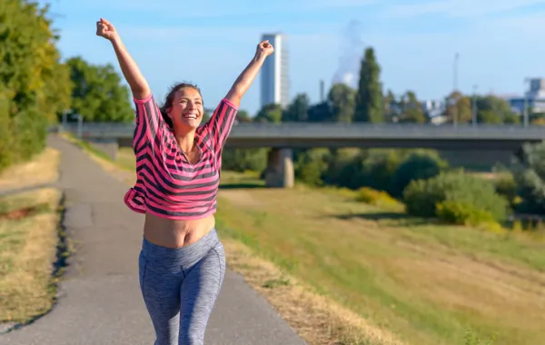 Foto de una chica joven haciendo ejercicio al aire libre y sonriendo
