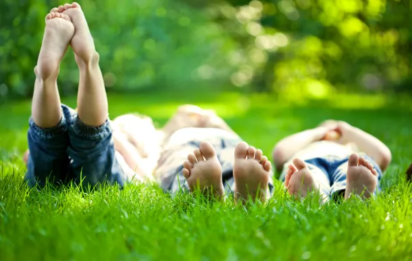 Foto de una familia tumbada en la hierba y con los pies descalzos