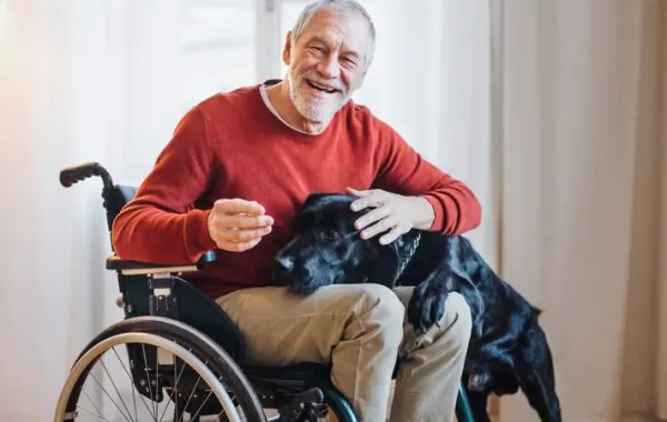 Foto de un hombre mayor en silla de ruedas alegre abrazando a su perro