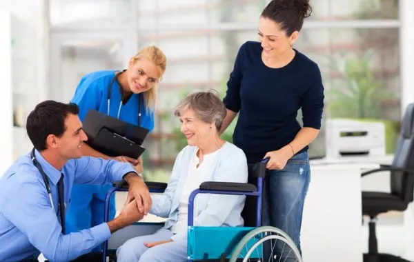 Mujer sonriente en silla de ruedas acompañada por familiares y personal médico