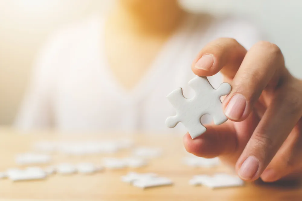 Foto de una mujer de la mano de una mujer que sostiene una pieza de un puzzle en su mano