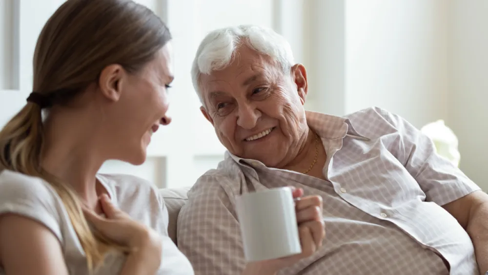 Foto de un anciano y una chica joven hablando y tomando un café