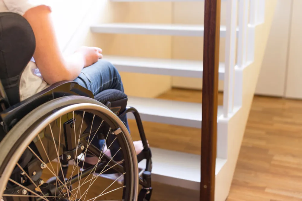Foto de una persona en silla de ruedas delante de una escaleras