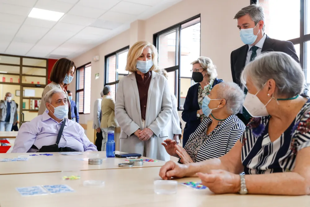 Foto de un centro social con varias personas mayores hablando en grupo con una trabajadora social