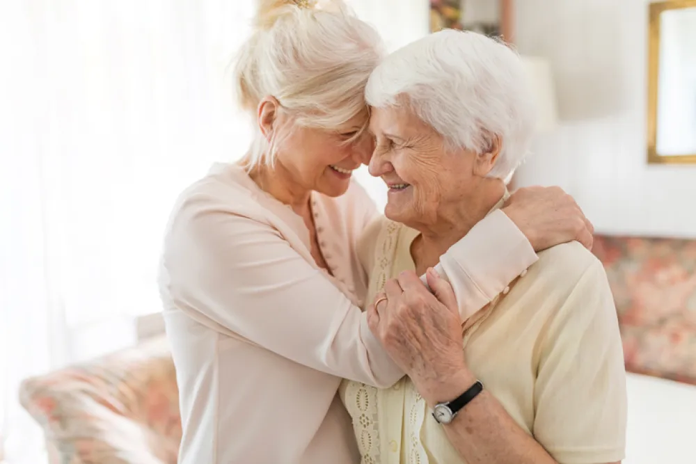 Foto de una señora mayor acompañada por otra señora más joven que la abraza
