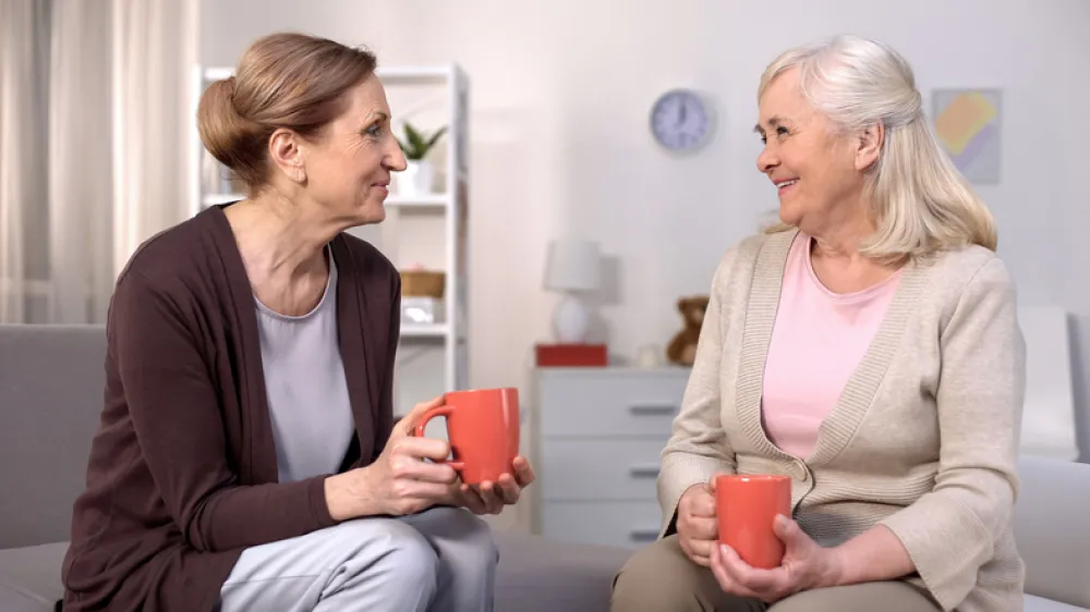 Foto de una señora mayor tomando un cafe y charlando con otra señora más joven