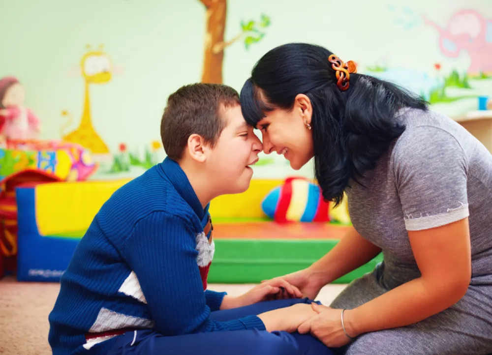 Foto de un niño con paralisis cerebral mirando a su madre y sonriendo