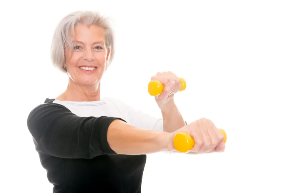 Foto de una mujer mayor haciendo ejercicio de brazos con unas pesas pequeñas
