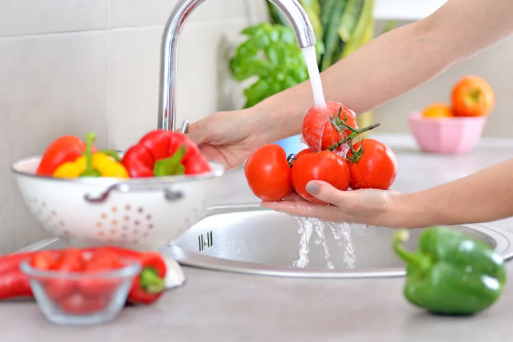 Foto de una manos que están lavando varias verduras