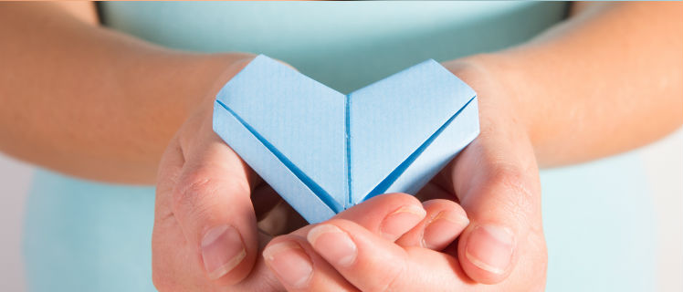 Foto de unas manos sosteniendo un corazón hecho en papel de color azul