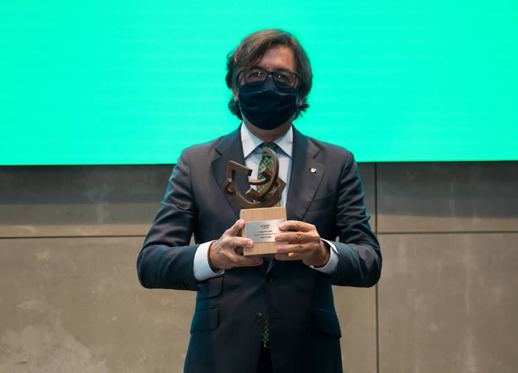 Fotografía de hombre con mascarilla sosteniendo un trofeo
