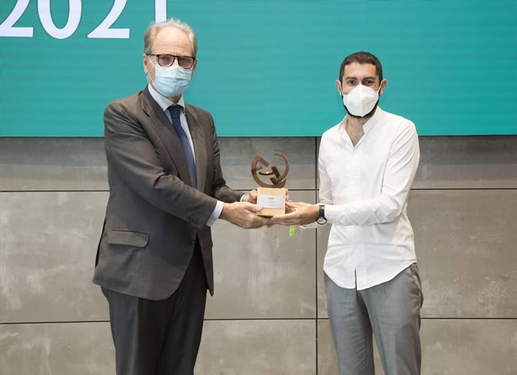 Fotografía de 2 hombre con mascarilla sosteniendo un trofeo