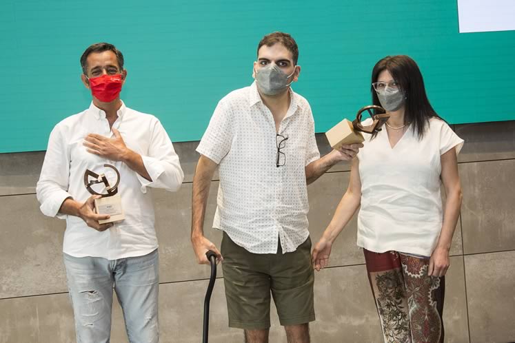 Fotografía de mujer y 2 hombre con mascarilla sosteniendo un par de trofeos