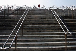 Persona subiendo escaleras urbanas anchas con muchos peldaños.
