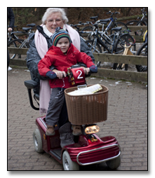 mujer mayor en una moto adaptada de cuatro ruedas en la que lleva a un niño pequeño