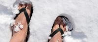 Foto de unos pies en chanclas de verano pisando la nieve