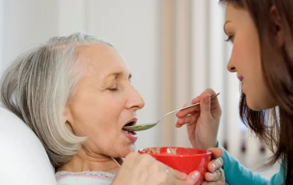 persona ayudando a comer a persona mayor