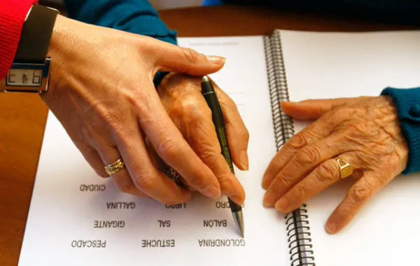 Foto de una persona ayudando a otra a escribir