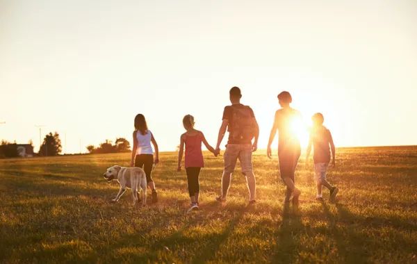 Foto de una familia que pasea por un campo al atardecer