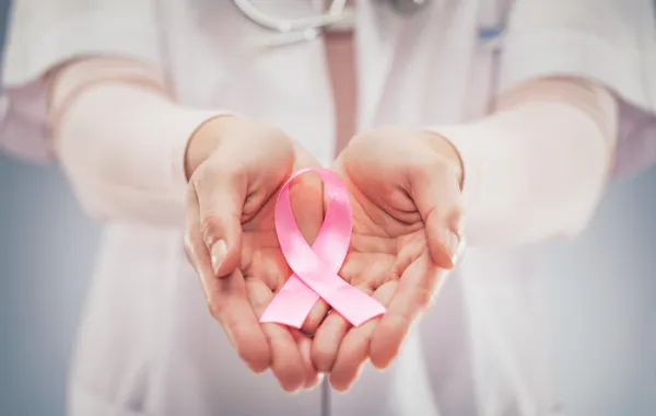 Foto de unas manos que sostienen un lazo rosa