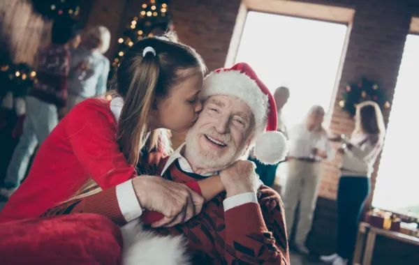 Foto de una nieta que abraza a su abuelo vestido de papa noel
