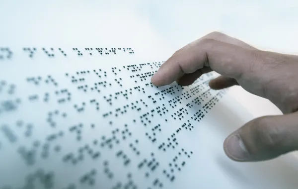 Foto de una mano leyendo un texto en braille