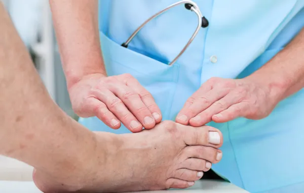 Foto de un pie que está siendo reconocido por las manos de un medico