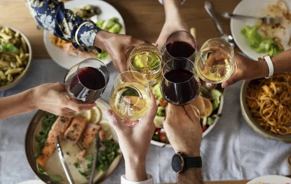 Foto de una mesa desde arriba con comida y con copas brindando