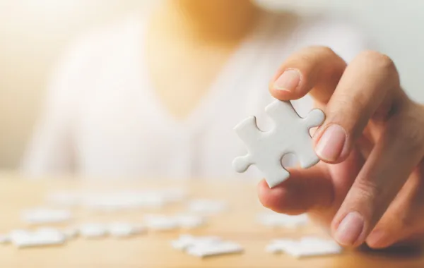 Foto de una mujer de la mano de una mujer que sostiene una pieza de un puzzle en su mano