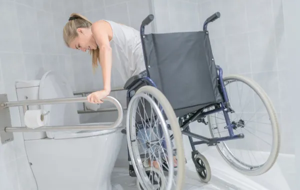 Foto de una mujer joven en silla de ruedas accediendo a un baño publico accesible