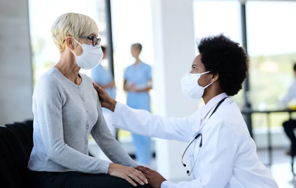 Foto de una señora mayor sentada en un silla y atendida por una doctora