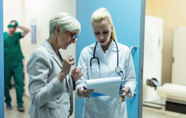 Foto de dos doctoras que conversan mientras observan un informe médico