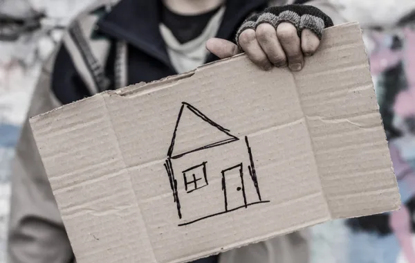 Foto de una  persona sosteniendo un cartón con una casa dibujada