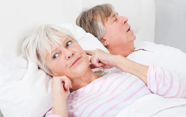 Foto de una pareja durmiendo mientras una mujer se tapa los oidos