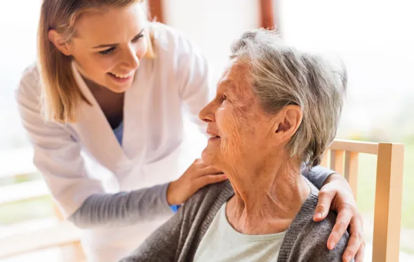 Foto de una señora mayor acompañada por una trabajadora social joven