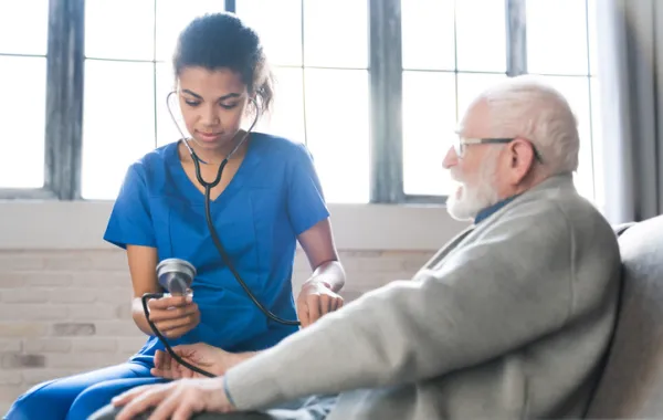 Foto de un señor mayor atendido por una medico en su casa