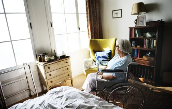 Foto de una mujer mayor en silla de ruedas que está sola en una habitación
