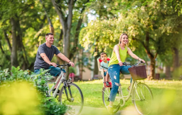 Foto de una pareja con un niño montando en bicicleta por un parque