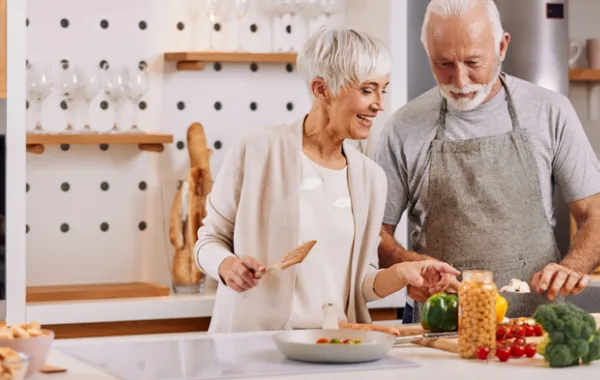 Foto de dos personas mayores cocinando comida saludable