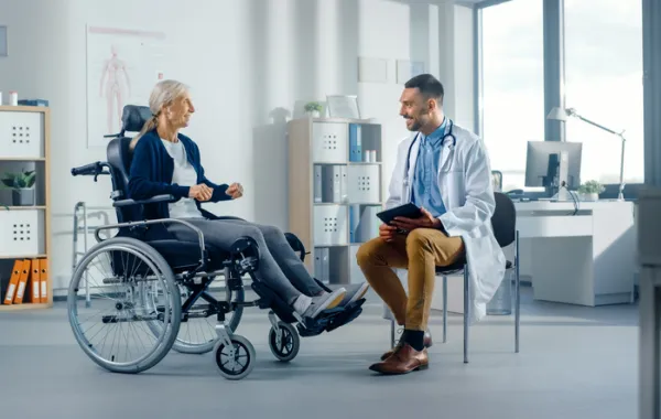 Foto de una señora en silla de ruedas hablando con un medico