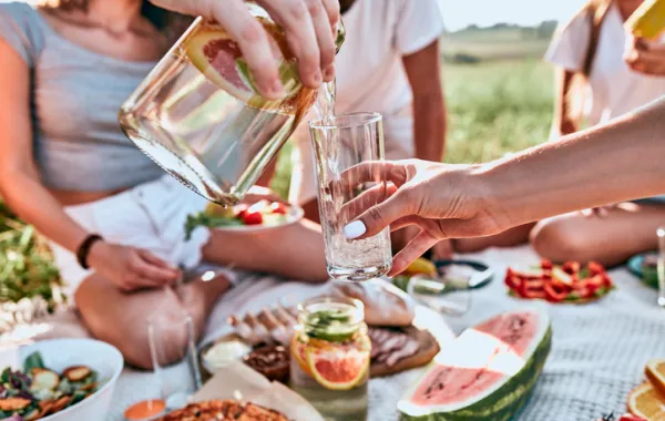 Foto de varias personas sentadas haciendo picnic y con una jarra de agua